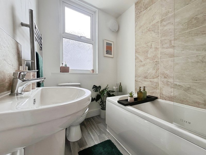 Modern bathroom with circular sink, bathtub, heated towel rail and window