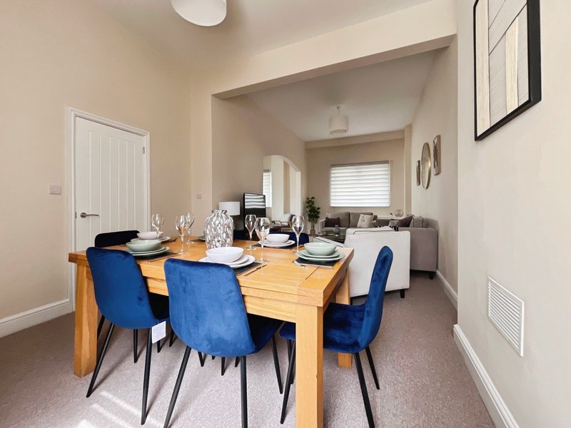 Dining room with wooden table, blue chairs, and view into kitchen beyond