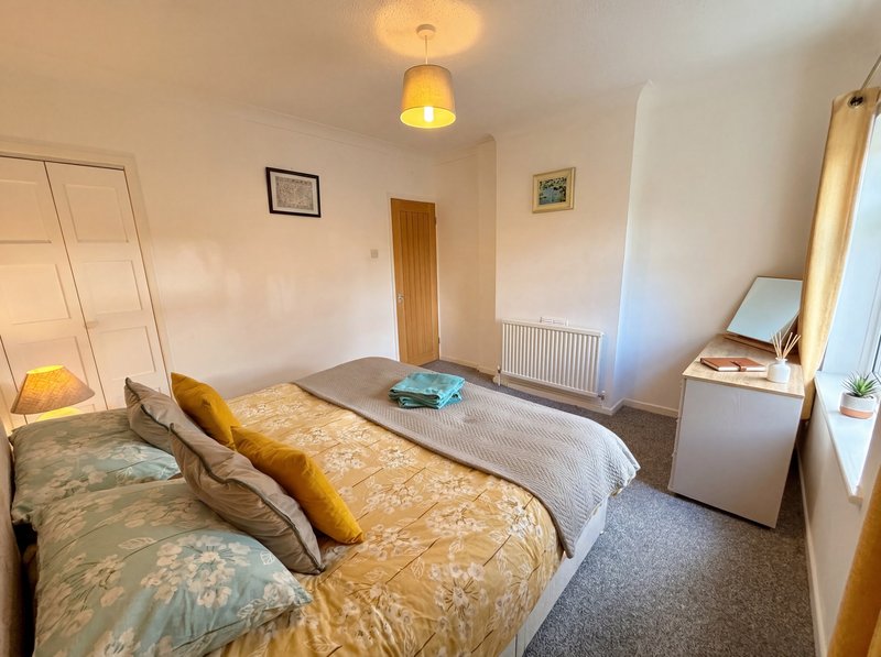 Bright bedroom with two single beds, yellow cushions, wooden door and radiator