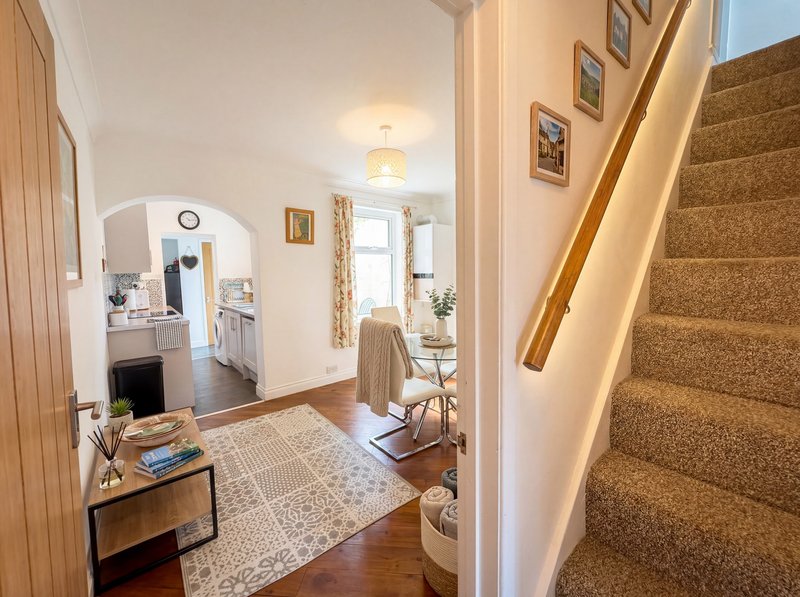 Hallway with staircase, desk, mirror, and doorway to kitchen area
