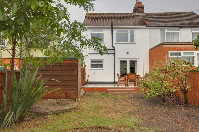 Semi-detached house exterior with patio, garden, wooden fence and mature landscaping