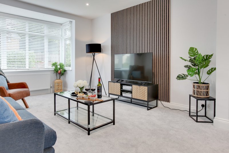 Modern living room with sofa, coffee table, TV stand, potted plants and floor lamp