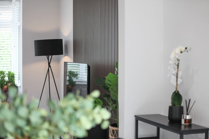 Modern interior with tripod floor lamp, potted plants, white orchid, and black console table