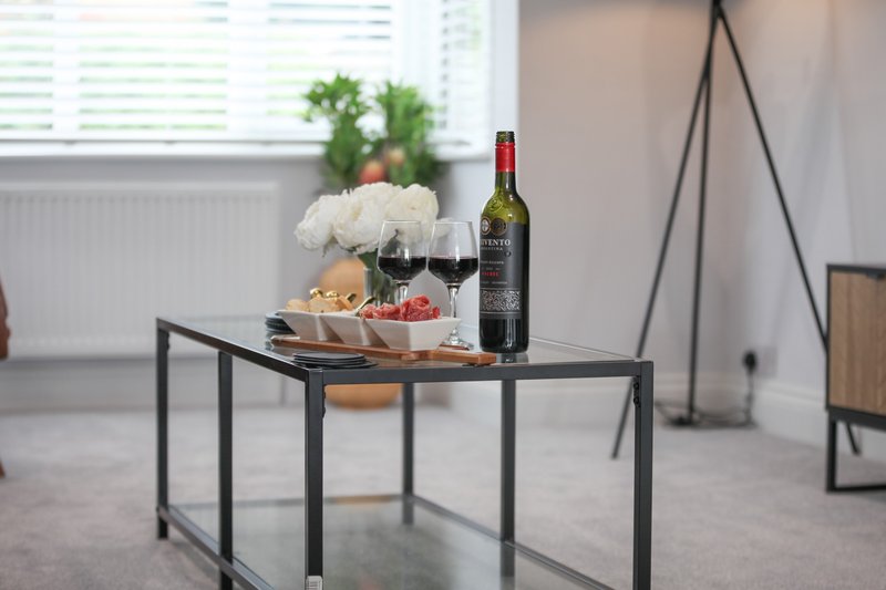 Styled dining table with wine bottle, glasses, flowers and fresh fruit in bright room