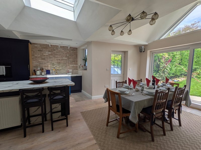 Open-plan kitchen and dining area with skylight, brick feature wall, dining table and chairs