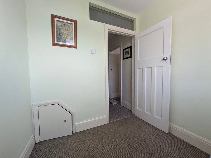 Hallway with brown carpet, white doors, framed map on wall, and storage box