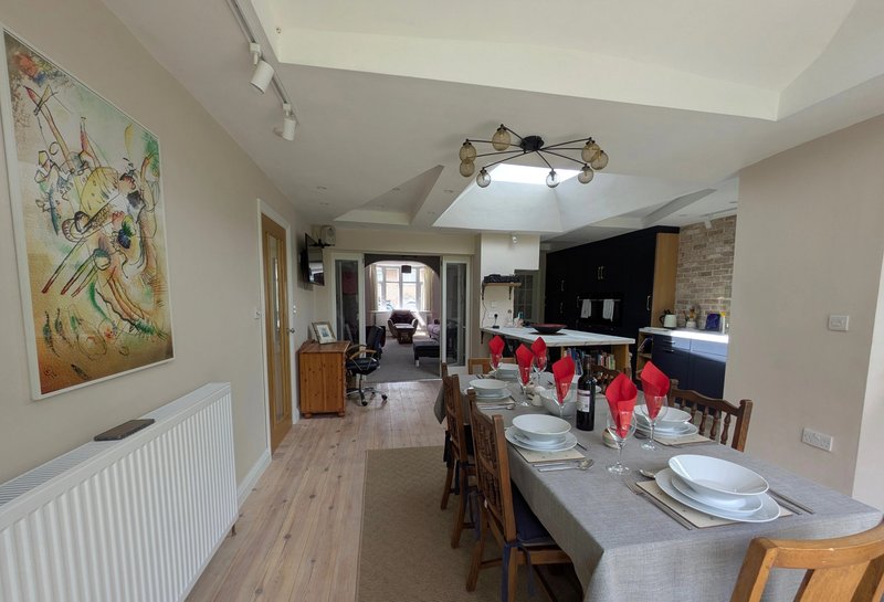 Open-plan kitchen and dining area with wooden table, red chairs, and artwork on wall