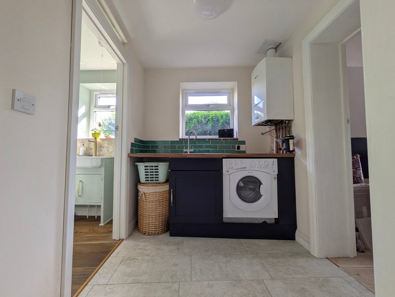 Utility room with washing machine, sink, counter space and access to garden