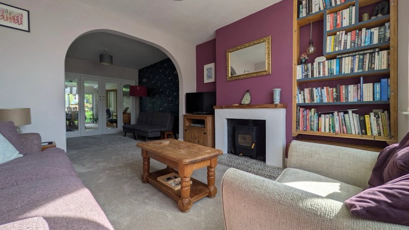 Open-plan living room with fireplace, bookshelves, purple accent wall and wooden coffee table