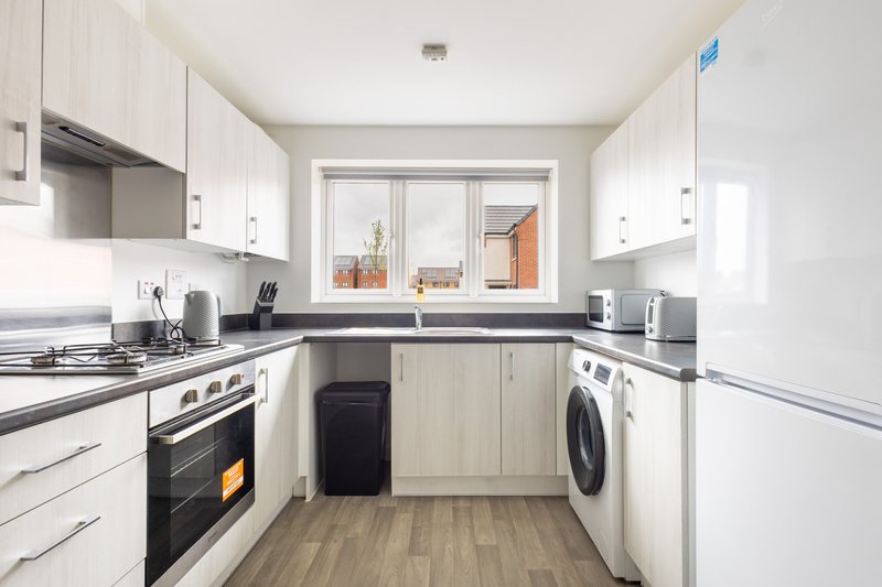 Modern galley kitchen with white cabinets, stainless steel appliances and washing machine