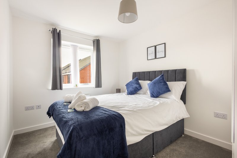 Modern bedroom with double bed, blue bedding, grey headboard and pendant light