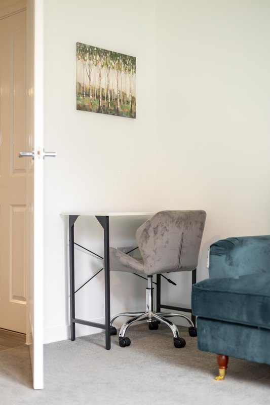 Bedroom corner with desk, upholstered chair, framed wall art and teal sofa