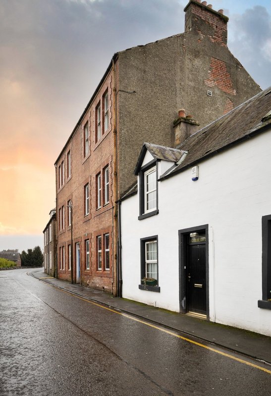 Exterior street view of traditional brick and white-rendered cottage with period windows and chimney