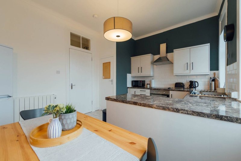 Modern kitchen-dining area with wooden table, granite countertop, and dark accent wall