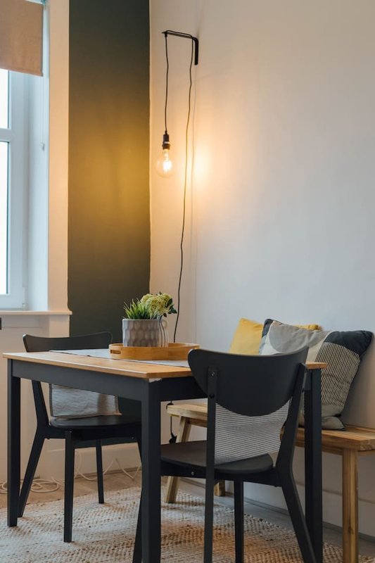 Modern workspace with black dining table, chairs, pendant lamp and potted plant