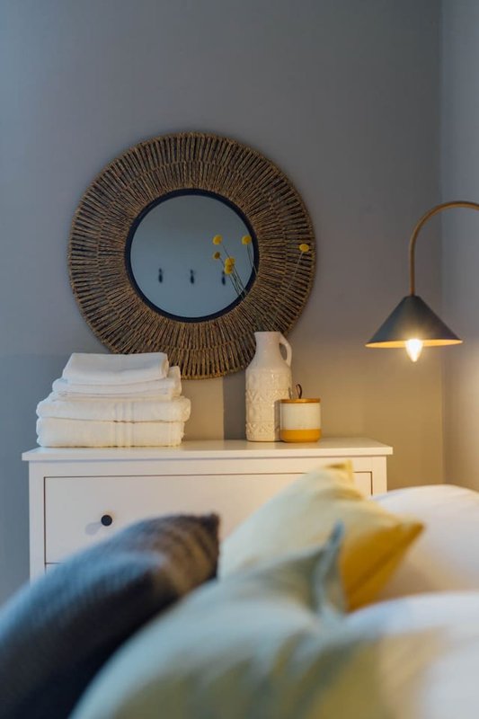 Bedroom nightstand with decorative mirror, stacked towels, candle and pendant lamp