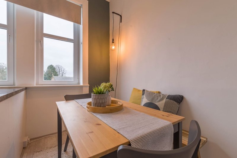 Dining area with wooden table, chairs, window, and potted plant decoration