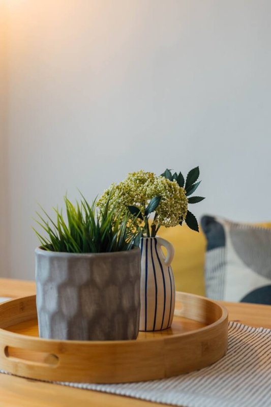 Wooden table with potted plant, vase with dried flowers, and decorative items