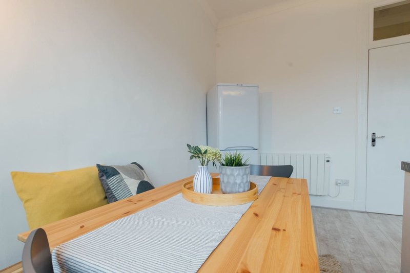 Bright modern bedroom with wooden bed frame, yellow cushion, potted plants and white wardrobe