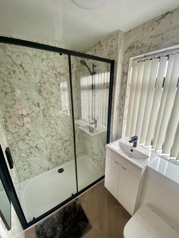 Modern bathroom with walk-in shower, white vanity sink, and vertical blinds