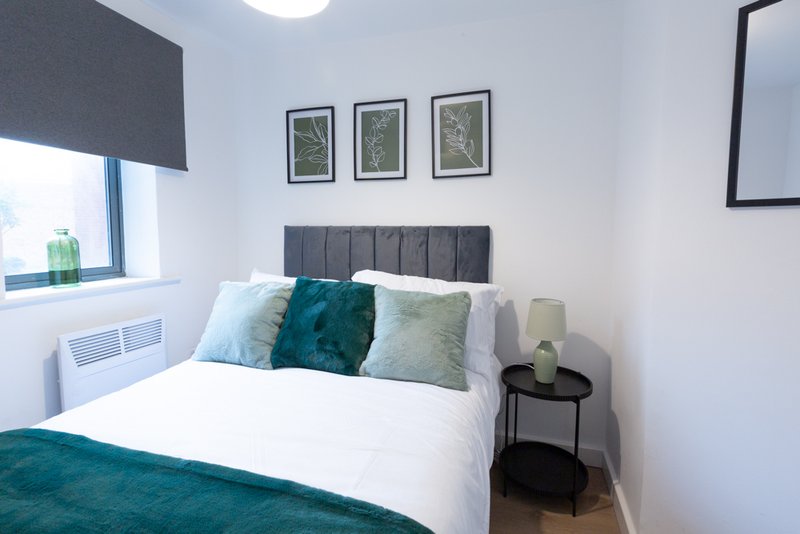 Modern bedroom with double bed, grey headboard, teal bedding, and framed wall art