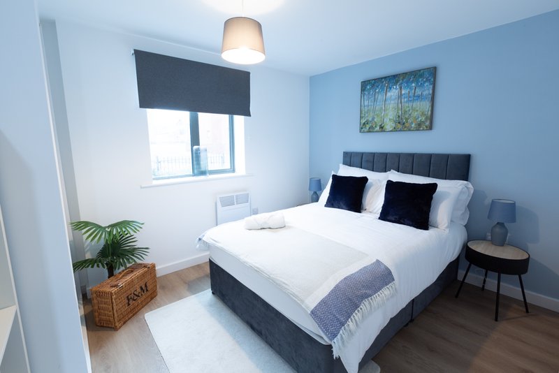 Modern bedroom with double bed, black headboard, white bedding, pendant light and window