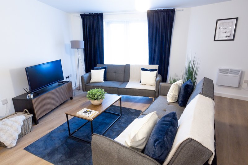 Bright modern living room with blue accents, sofas, TV, coffee table and large windows