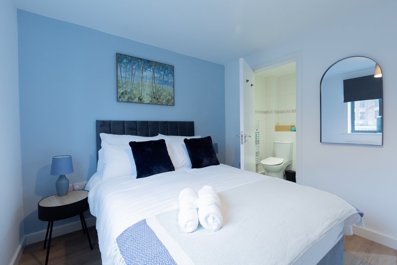 Modern bedroom with double bed, blue walls, black headboard and bedside table