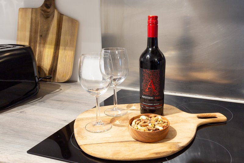 Kitchen counter with wine bottle, glasses, wooden boards and snacks arranged on marble surface