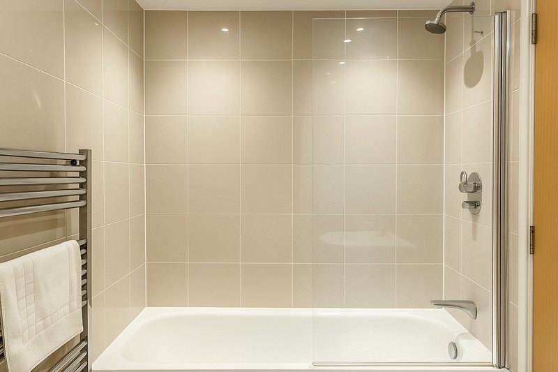 Modern bathroom with white tile walls, glass shower enclosure and towel warmer