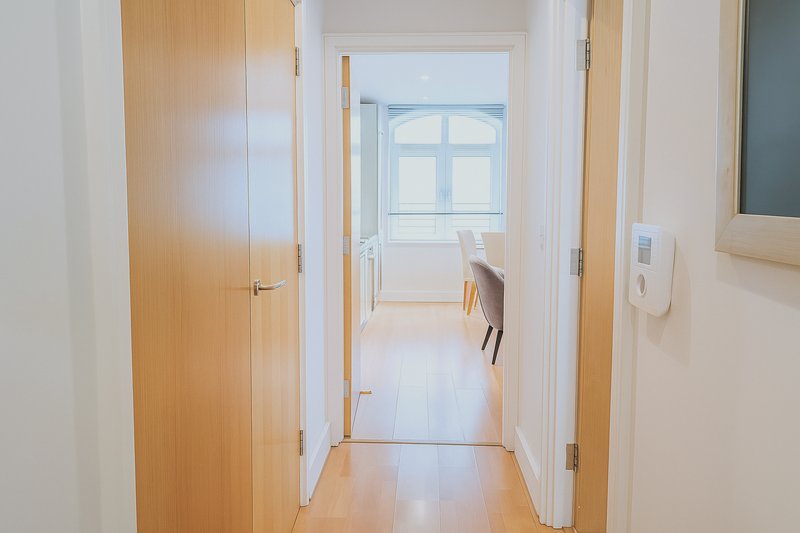 Bright hallway with wooden doors, white walls, and natural light from window