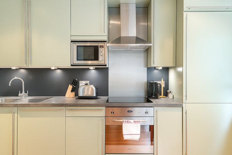 Modern kitchen with cream cabinets, dark backsplash, stainless steel appliances and granite countertop