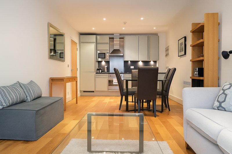 Open-plan living area with kitchen, dining table, sofas and wooden flooring