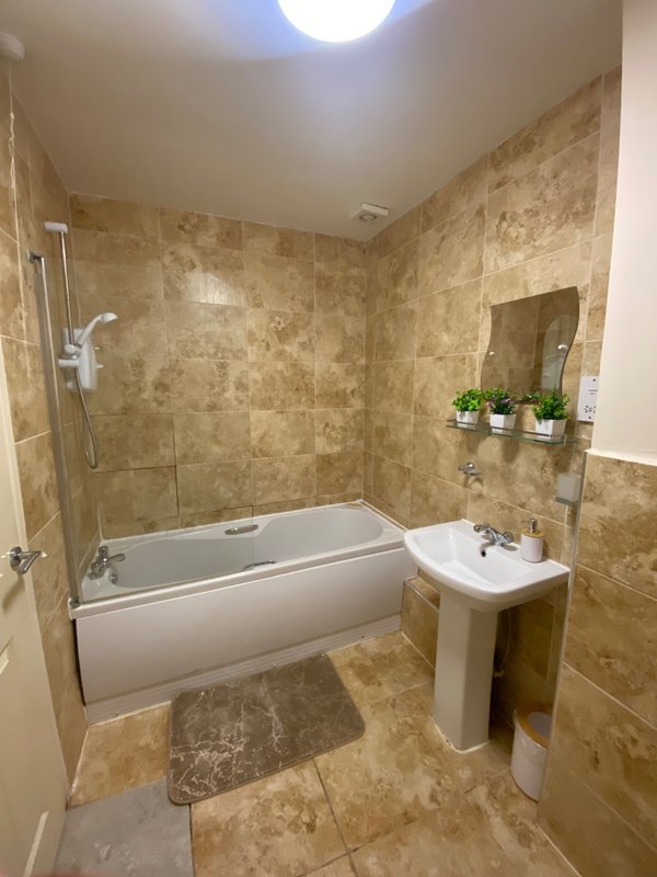 Modern bathroom with bathtub, pedestal sink, tiled walls and skylight window