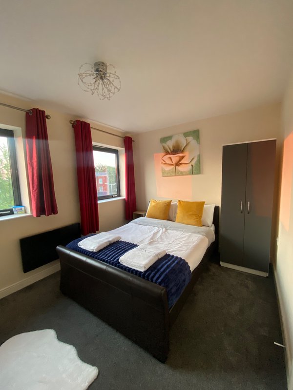 Bedroom with double bed, burgundy curtains, pendant light, wall art and wardrobe