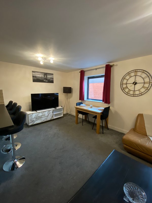 Living room with TV, desk, dining table, armchair and wall clock