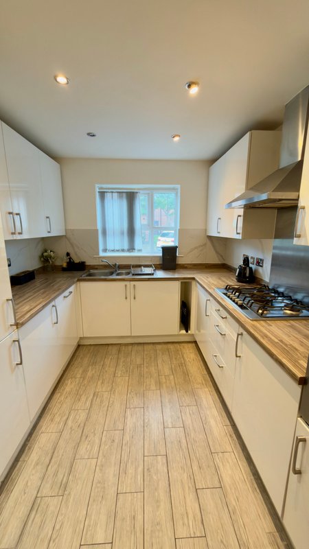 Modern kitchen with cream cabinets, wooden countertops, gas hob, and wood-effect flooring