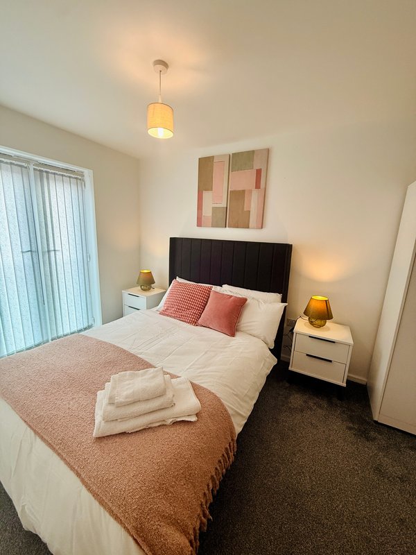 Modern bedroom with double bed, black headboard, bedside tables, pendant light, and abstract wall art