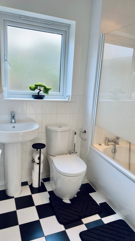 Bathroom with toilet, pedestal sink, window, and black-and-white checkered floor