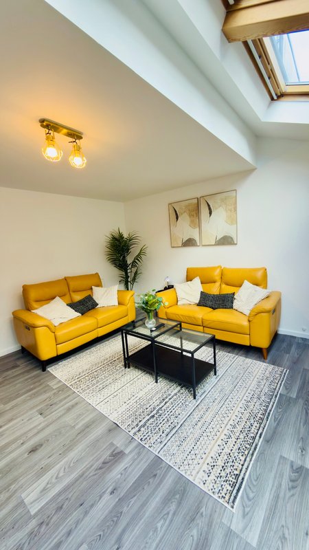 Modern living room with two yellow sofas, black coffee table, skylight and potted plants