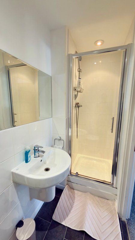 Modern bathroom with round white sink, mirror, shower cubicle and herringbone floor