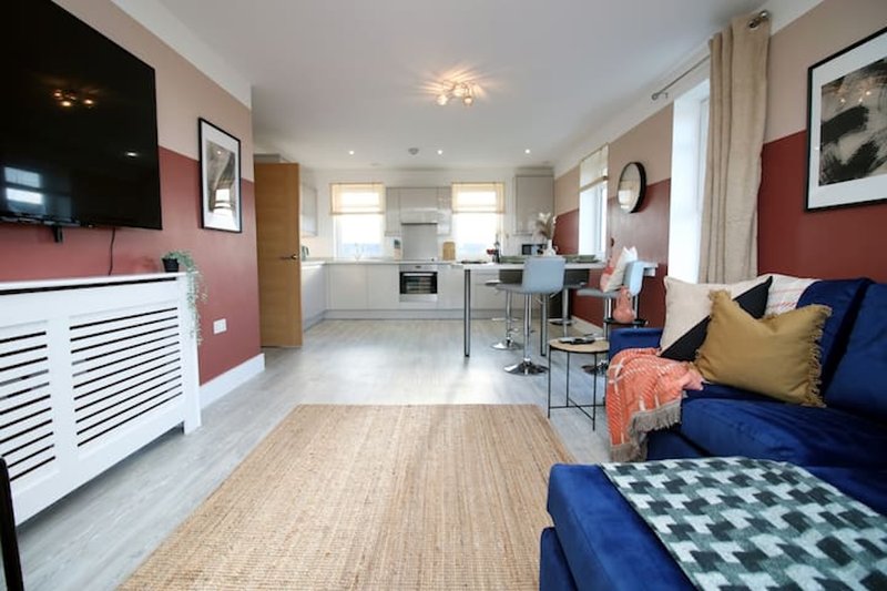 Open-plan living space with kitchen, dining area, sofa and bedroom furnishings