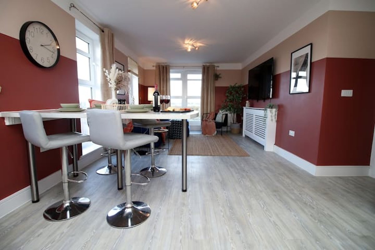 Open-plan living space with red accent walls, dining table, kitchen area, and modern furnishings