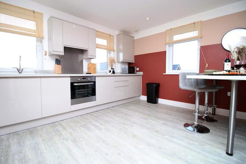 Modern kitchen with white cabinetry, black oven, red accent wall and breakfast bar