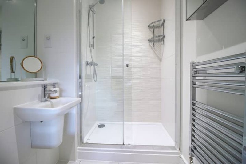 Modern bathroom with white sink, enclosed shower cubicle, and heated towel rail