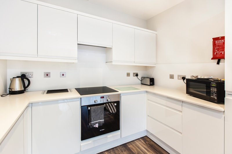 Modern white kitchen with built-in oven, induction hob, and wooden flooring