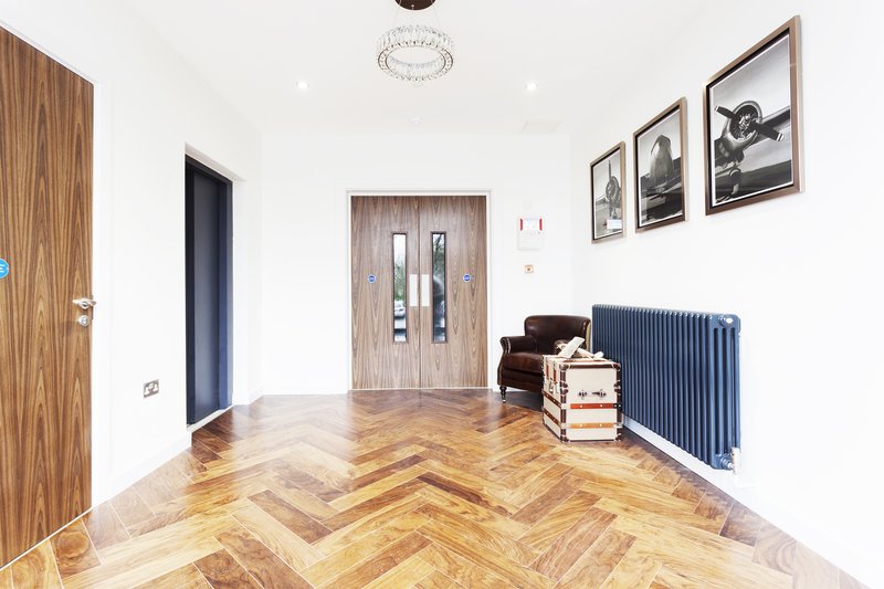 Bright hallway with herringbone wooden floor, wall art, radiator and interior doors