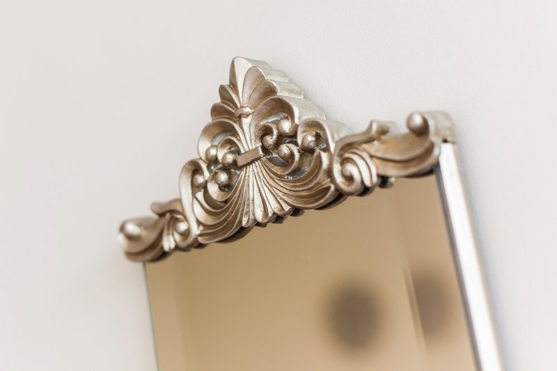 Ornate gold-framed mirror with decorative scrollwork crest detail