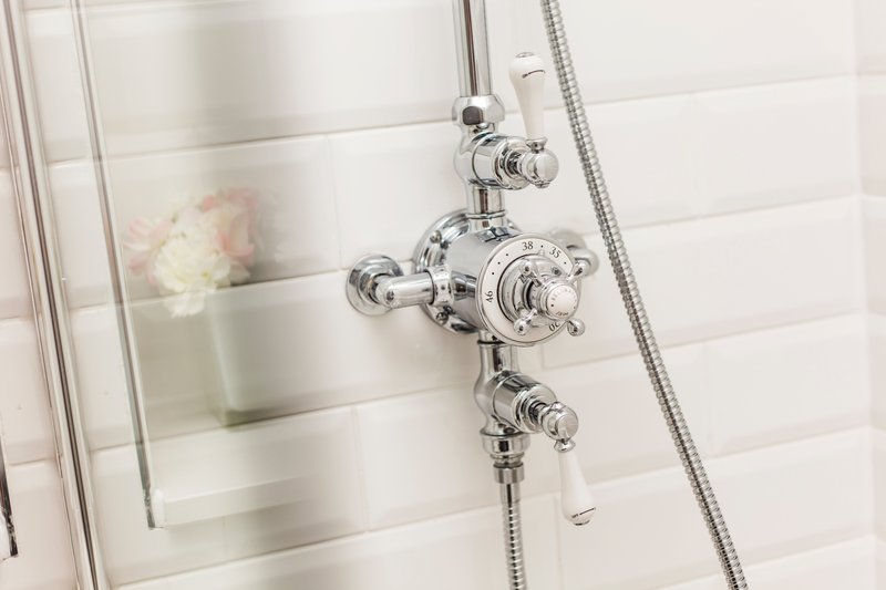 Modern bathroom shower with chrome thermostatic valve and white tile surround