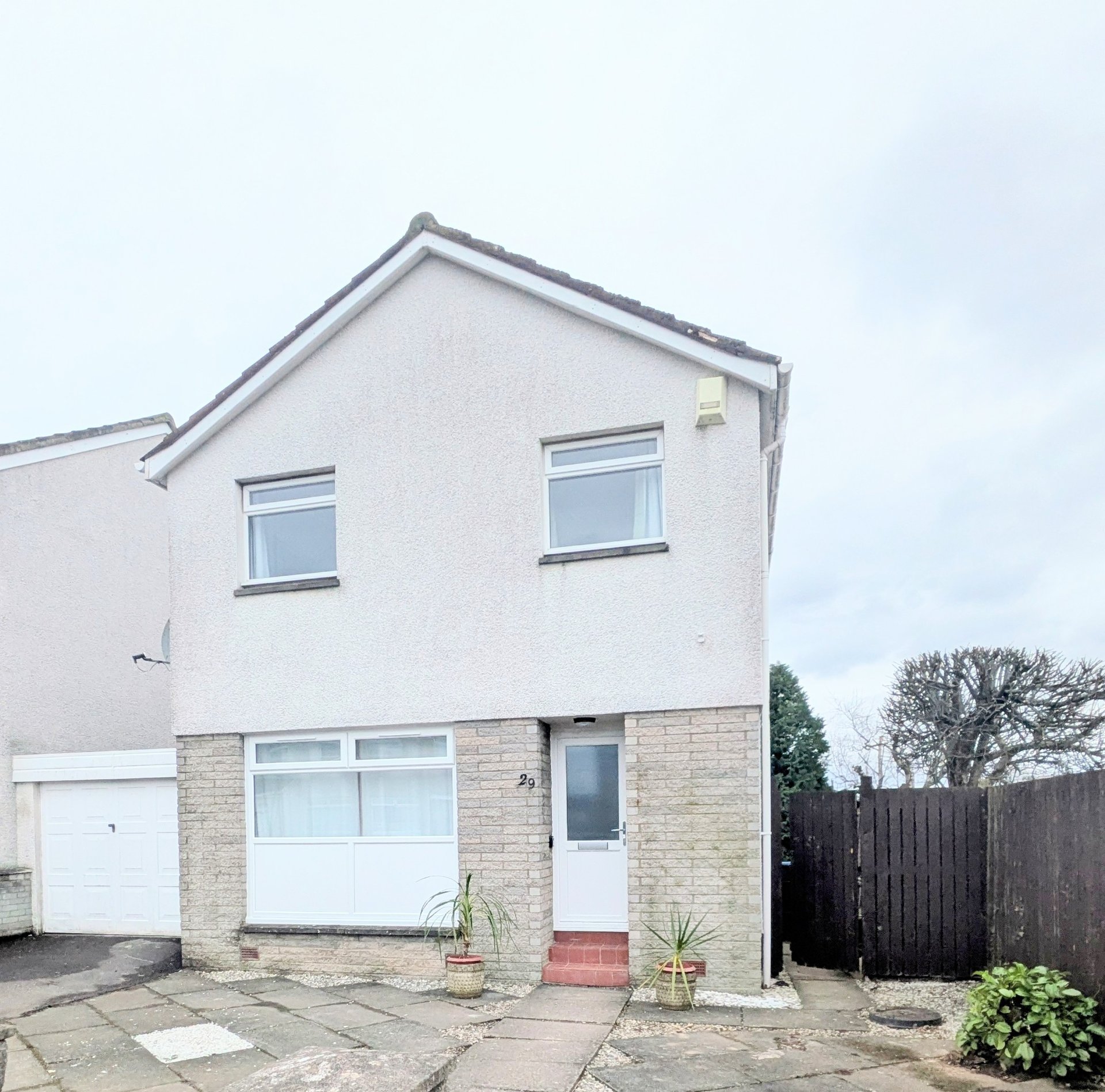 Modern two-storey house with white render, stone base, garage and driveway